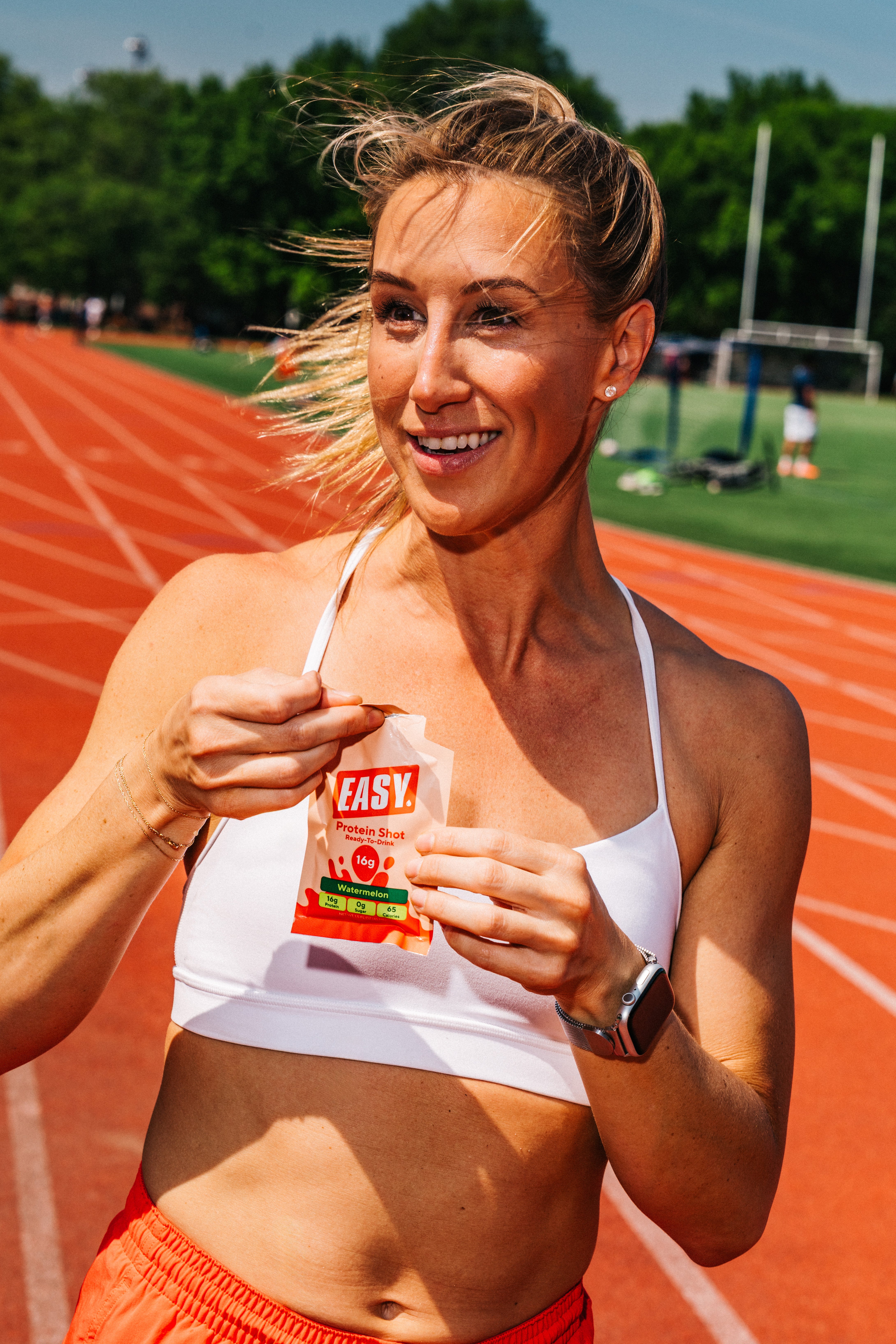 Easy Protein® model on a running track holding a Watermelon protein shot
